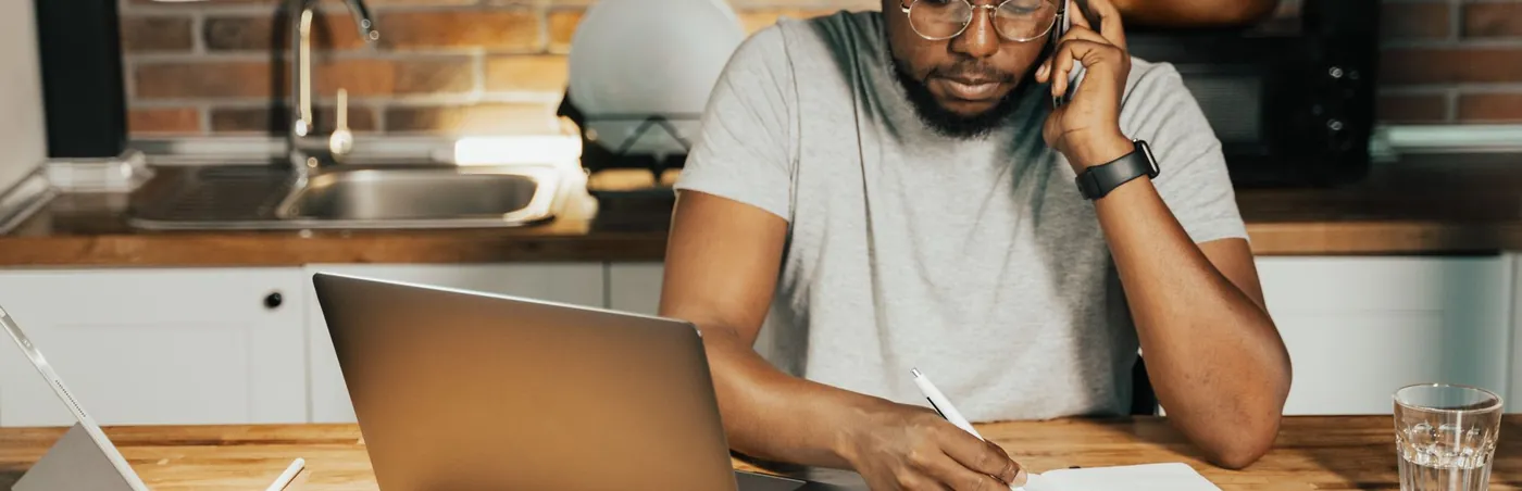 Adult learner coaching: a man studying at his kitchen counter with a laptop and notes